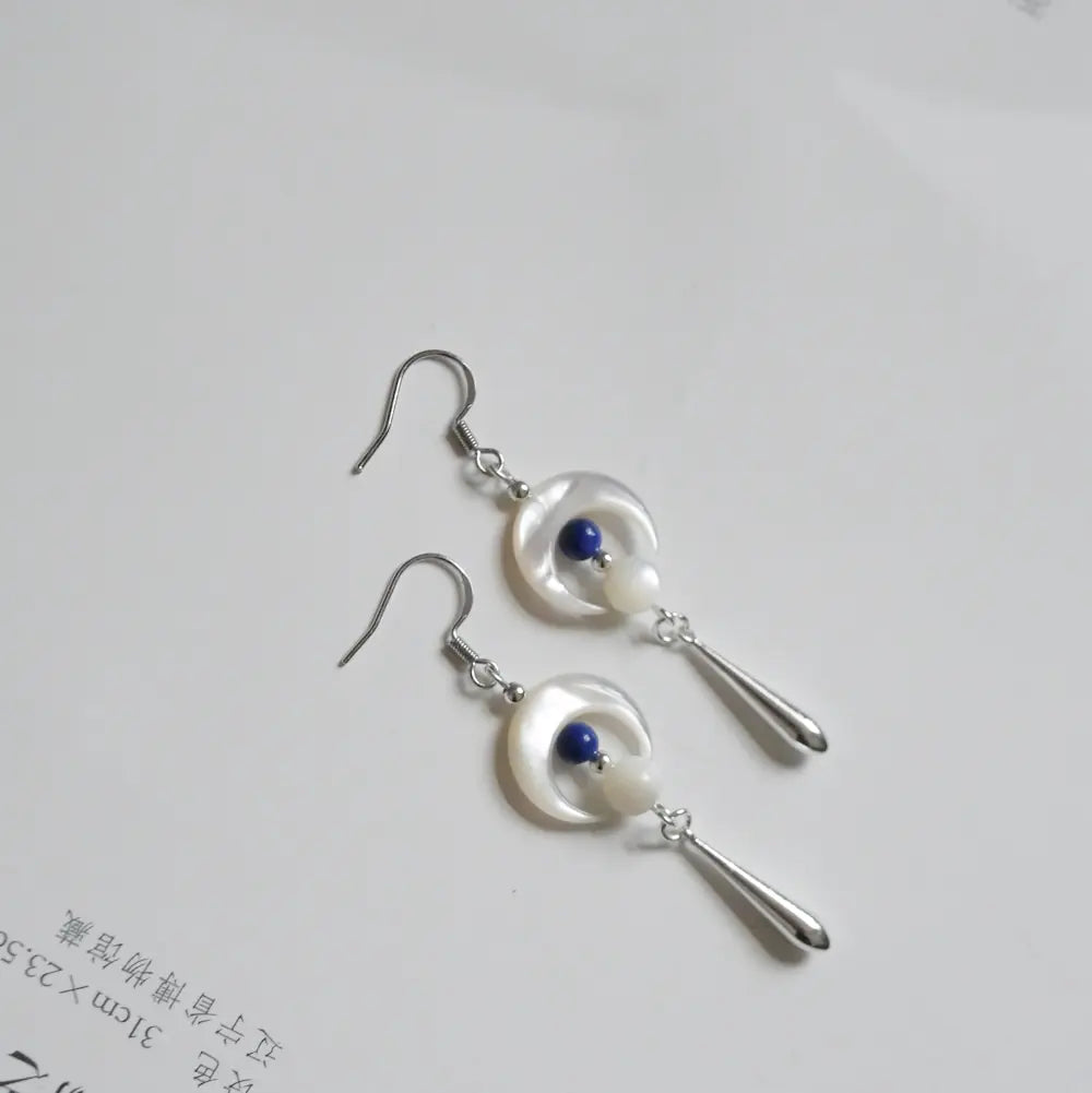 Close up flat lay of crescent moon earrings showing lapis lazuli bead and shell bead detail Orienlu