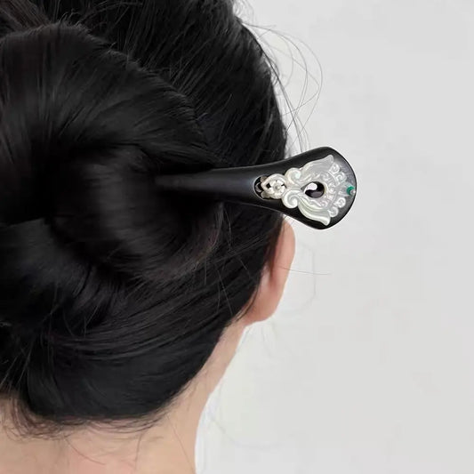 Rear view of a woman styling her long thick hair into a secure hair bun using the 18cm elegant ebony wood hairpin.