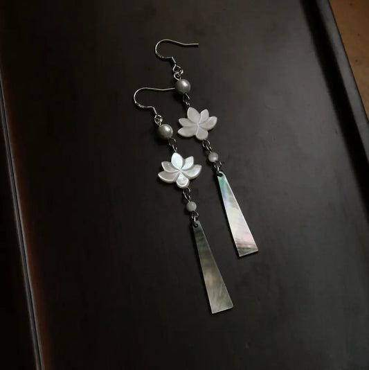 Close up of lotus flower earrings on dark tray showing carved MOP blossom detail Orienlu