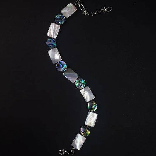Full length view of Mother of Pearl and iridescent abalone shell beaded bracelet laid in an S-curve — Orienlu