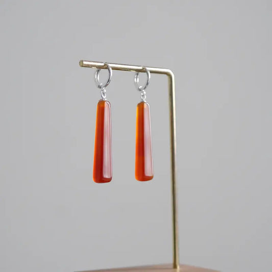 A front-view detail shot of the Orienlu red carnelian agate drop earrings, showcasing the smooth geometric cut of the gemstones and the silver-plated hardware.