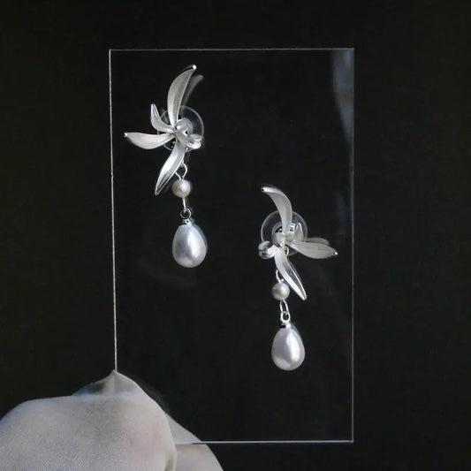 Close-up of carved shell flower and teardrop pearl pendant on pearl drop earrings