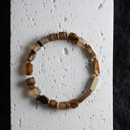 Top view of earth tone beaded natural stone bracelet featuring agate and quartz on a textured white background — Orienlu