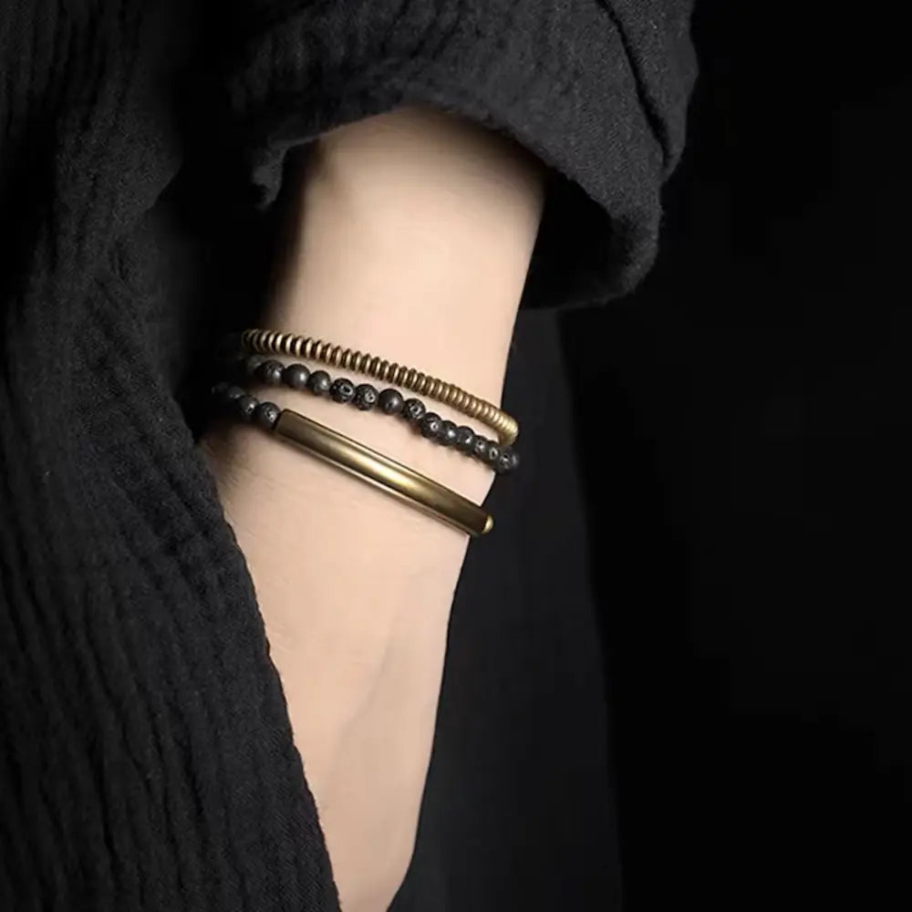 Black lava rock and brass bracelet worn as unisex natural stone accessory on wrist — Orienlu