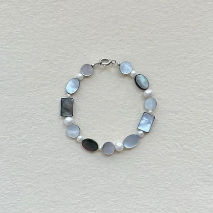 Handcrafted black mother of pearl and freshwater pearl geometric bracelet on textured paper surface Orienlu