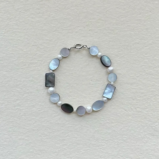 Handcrafted black mother of pearl and freshwater pearl geometric bracelet on textured paper surface Orienlu