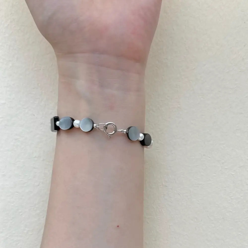Freshwater pearl bracelet mixed with black shell worn on wrist showing spring clasp Orienlu