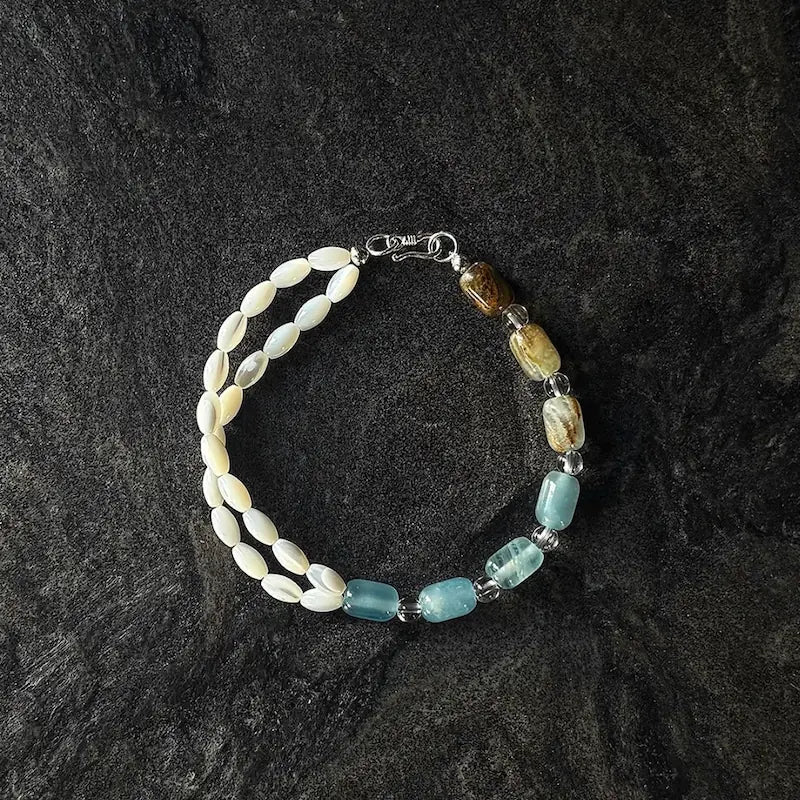 Handcrafted two-tone calcite and mother of pearl bracelet with S clasp on dark slate surface Orienlu
