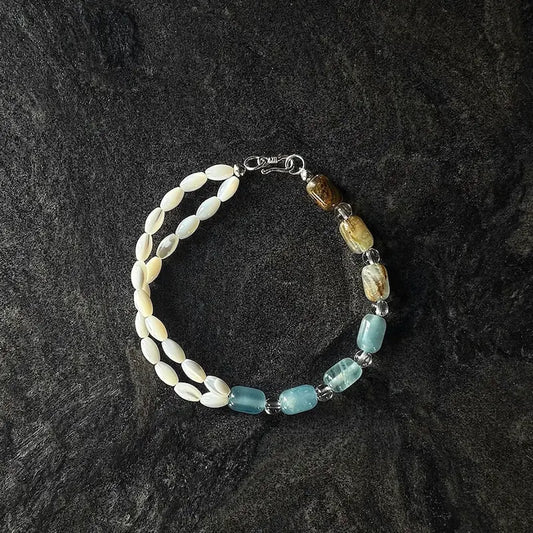Handcrafted two-tone calcite and mother of pearl bracelet with S clasp on dark slate surface Orienlu