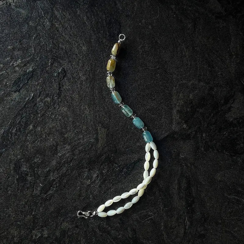 Unclasped two-tone bracelet laid out showing blue-yellow calcite barrel beads and white MOP strands Orienlu