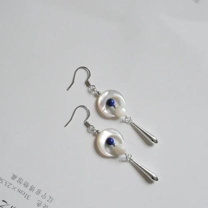 Close up flat lay of crescent moon earrings showing lapis lazuli bead and shell bead detail Orienlu