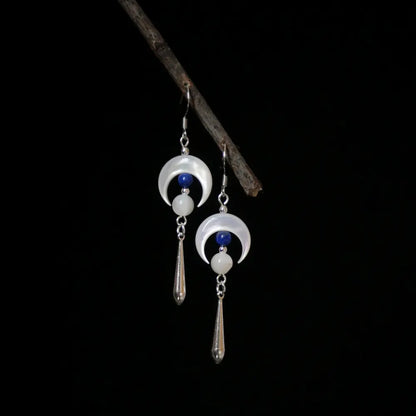 Silver moon earrings with mother of pearl crescent and lapis lazuli drop on dark background Orienlu