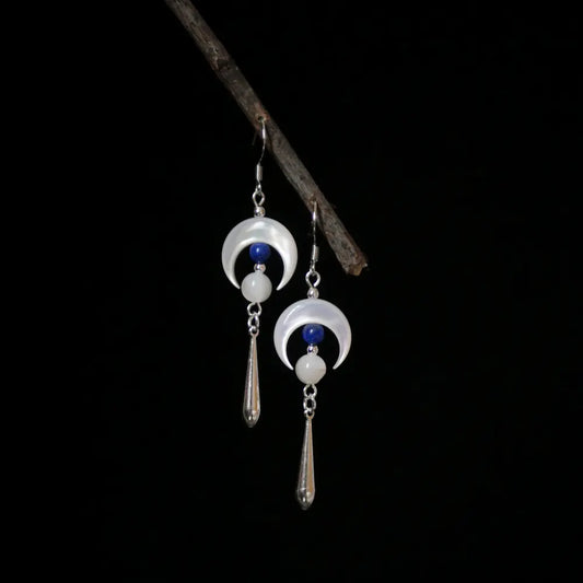 Silver moon earrings with mother of pearl crescent and lapis lazuli drop on dark background Orienlu