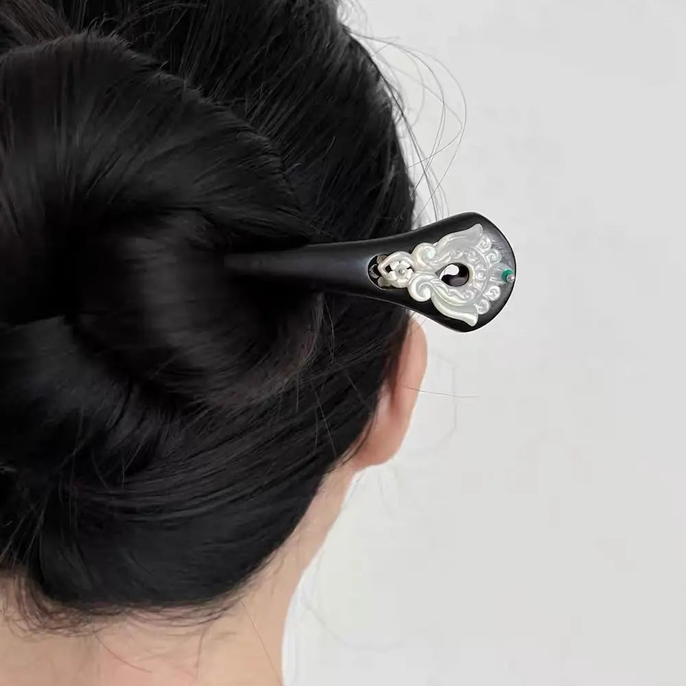 Rear view of a woman styling her long thick hair into a secure hair bun using the 18cm elegant ebony wood hairpin.