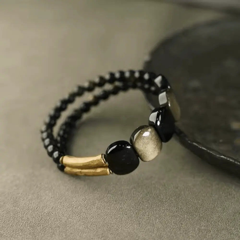 Close-up of gold sheen obsidian beads and textured copper tubes on protection bracelet — Orienlu