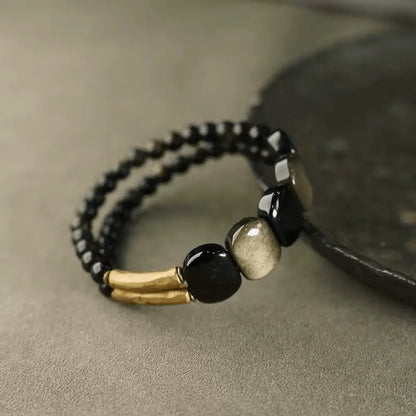 Close-up of gold sheen obsidian beads and textured copper tubes on protection bracelet — Orienlu
