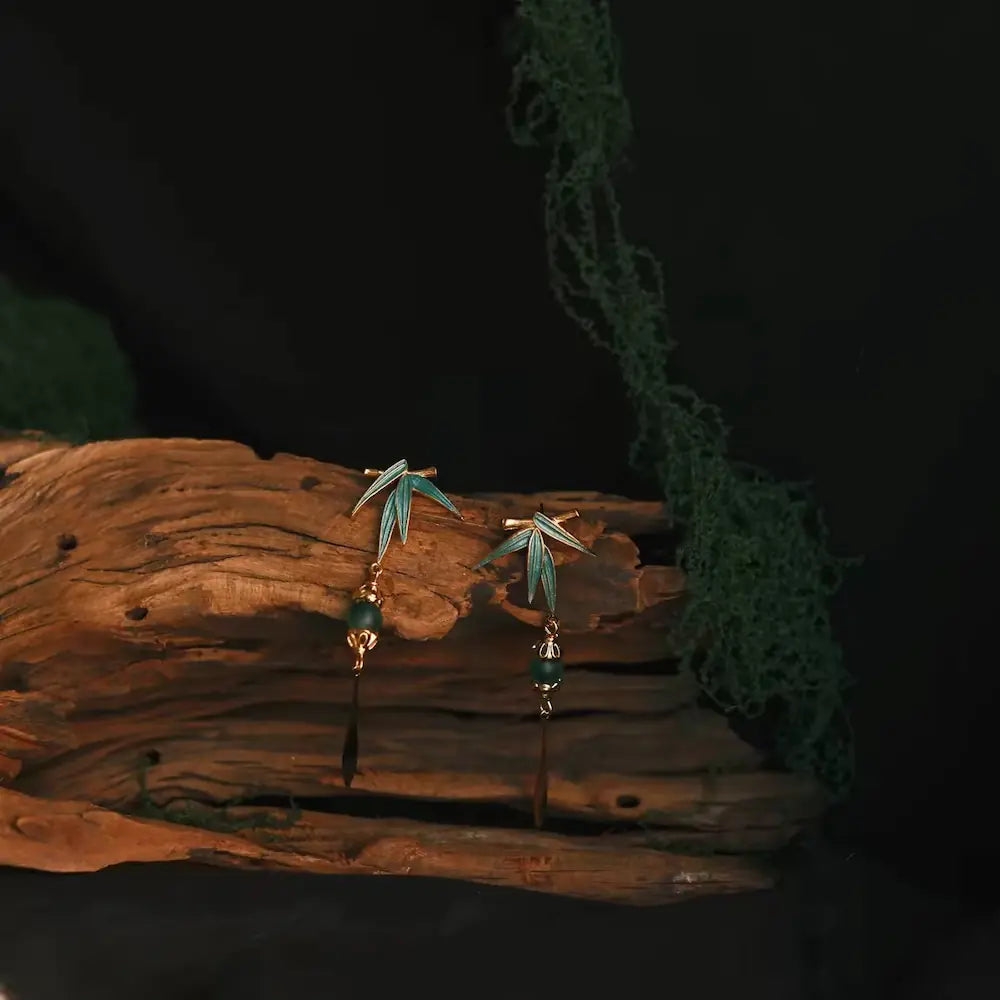 Green cloisonné bamboo leaf drop earrings displayed on natural vintage driftwood — Orienlu