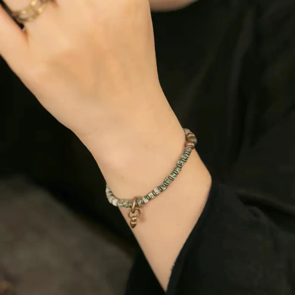 Green quartz healing bracelet with copper pendant worn with neutral outfit — Orienlu