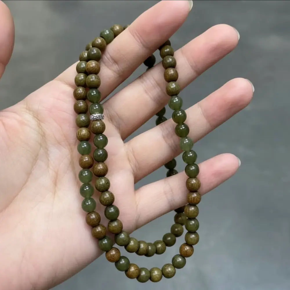 Close up of green sandalwood beads and dark green hetian jade held in hand Orienlu