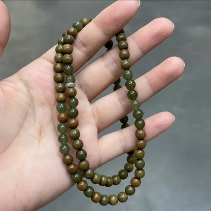 Close up of green sandalwood beads and dark green hetian jade held in hand Orienlu