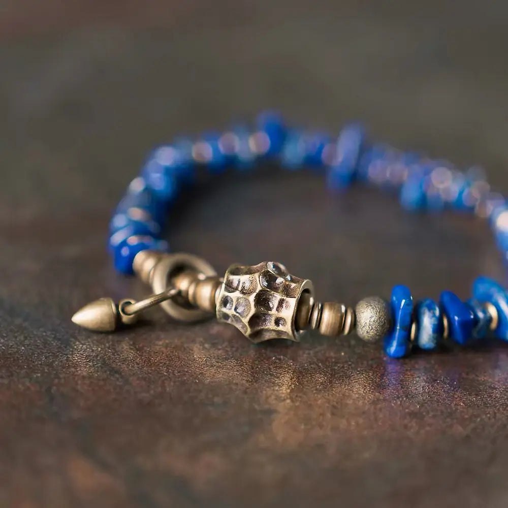Close-up of vintage brass pendant and hammered metal bead on lapis lazuli raw stone bracelet — Orienlu