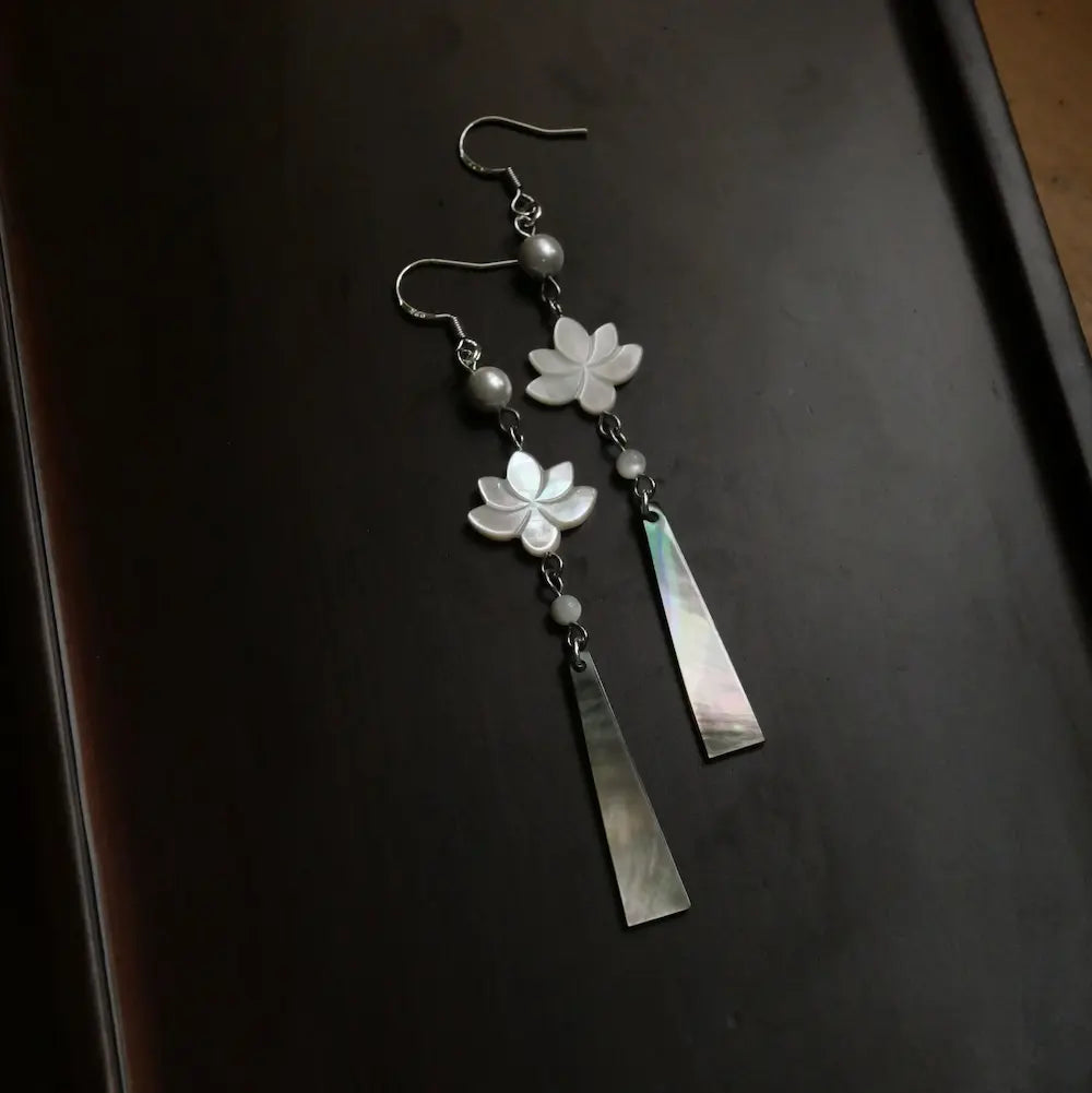 Close up of lotus flower earrings on dark tray showing carved MOP blossom detail Orienlu