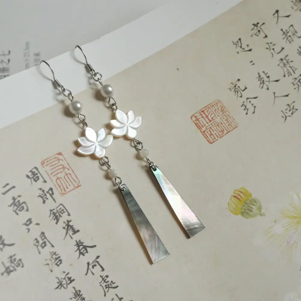 Long lotus drop earrings with iridescent black mother of pearl pendant on Chinese calligraphy background Orienlu