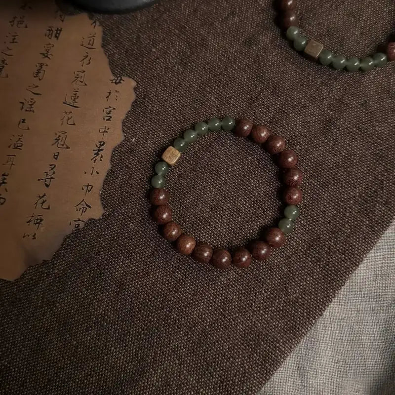 Close-up of hetian jade beads and square green sandalwood accent on wood and jade bracelet
