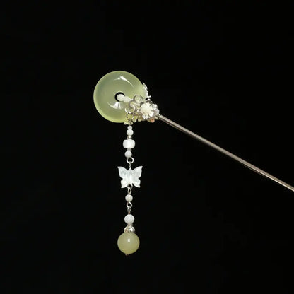 Studio view of the Orienlu gemstone hair stick showing the reverse construction, focusing on the alloy floral metalwork securing the pale green chalcedony disc and the link chain alignment.