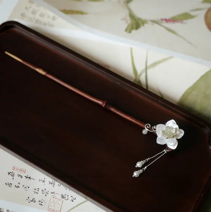 A beautiful top-down panorama shot of the full 20cm polished bamboo hair pin with distinct bamboo knots, resting on a dark wood tray with a traditional calligraphy background.
