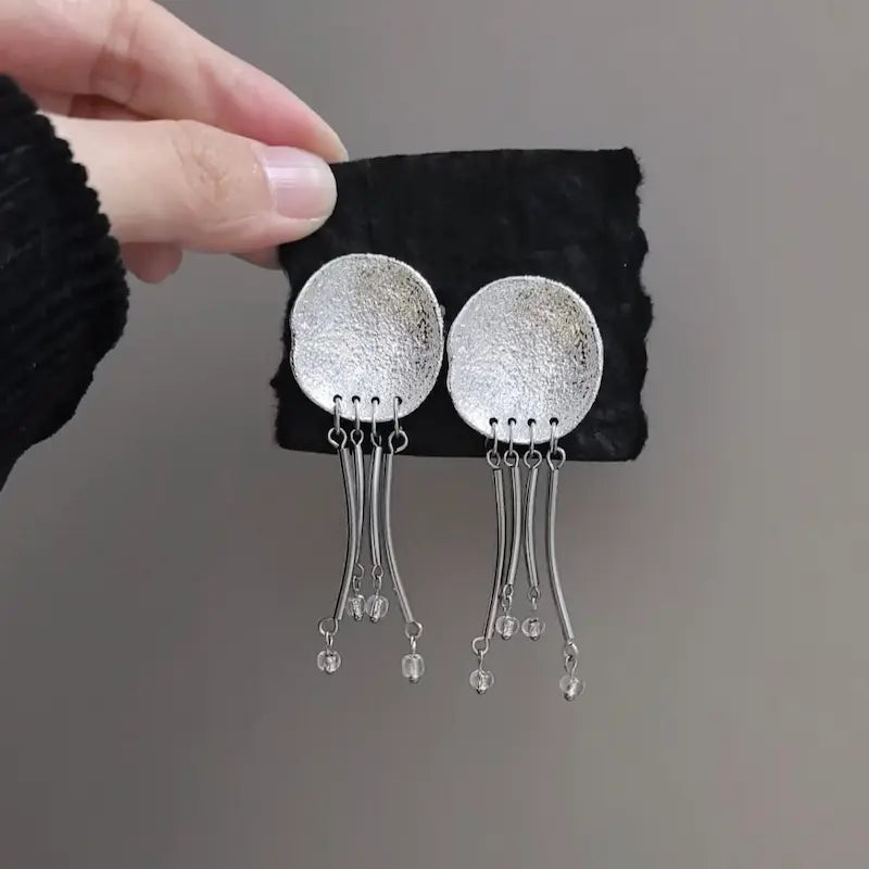 Close-up of hammered disc and clear crystal bead tips on jellyfish drop earrings
