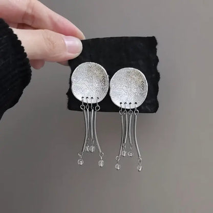 Close-up of hammered disc and clear crystal bead tips on jellyfish drop earrings
