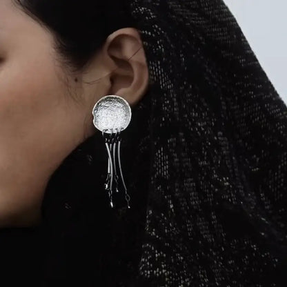Crystal jellyfish drop earrings worn with silver post stud on ear