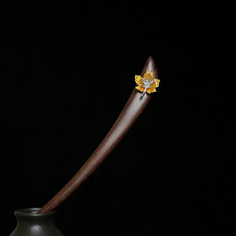 A striking studio shot of the Orienlu red sandalwood hair pin resting elegantly in a dark ceramic vase against a moody black background, highlighting its sleek curved silhouette.