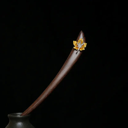 A striking studio shot of the Orienlu red sandalwood hair pin resting elegantly in a dark ceramic vase against a moody black background, highlighting its sleek curved silhouette.