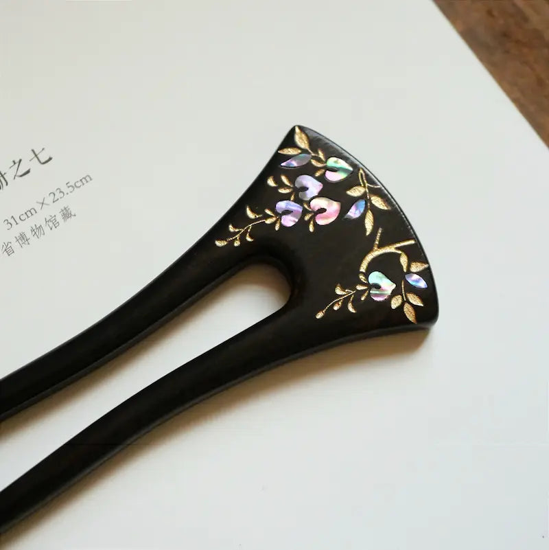An angled top-view display of the Orienlu raden shell inlay hair fork on a clean white paper background, highlighting the brilliant luster of the heart-shaped mother of pearl petals and gold details.