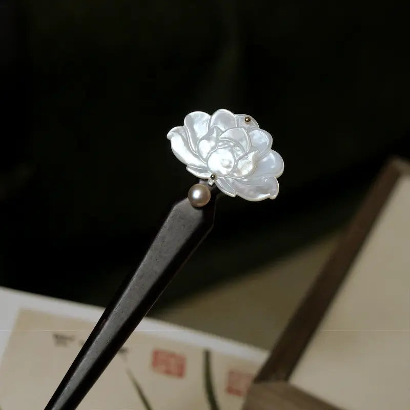 An alternative angled view of the tapered ebony wood hair pin, showcasing the smooth craftsmanship and premium natural materials against a traditional aesthetic backdrop.