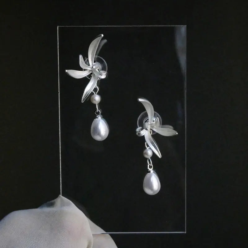  Close-up of carved shell flower and teardrop pearl pendant on pearl drop earrings