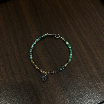 Handcrafted quartzite abacus stone bracelet with pinecone charm on dark wooden surface Orienlu