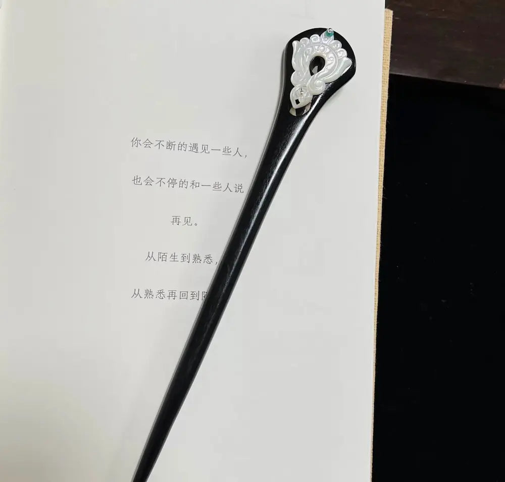 Full-length view of the 18cm vintage style oriental wooden hair stick resting on an open book, showcasing its elegant tapered design.