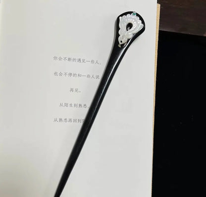 Full-length view of the 18cm vintage style oriental wooden hair stick resting on an open book, showcasing its elegant tapered design.