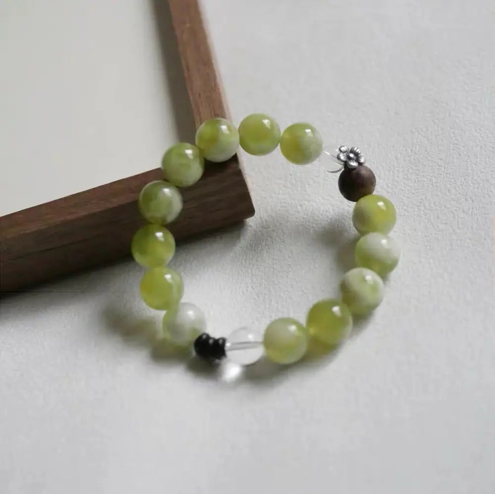 Close-up of xiuyu jade and silver flower charm on chinese zen bracelet — Orienlu